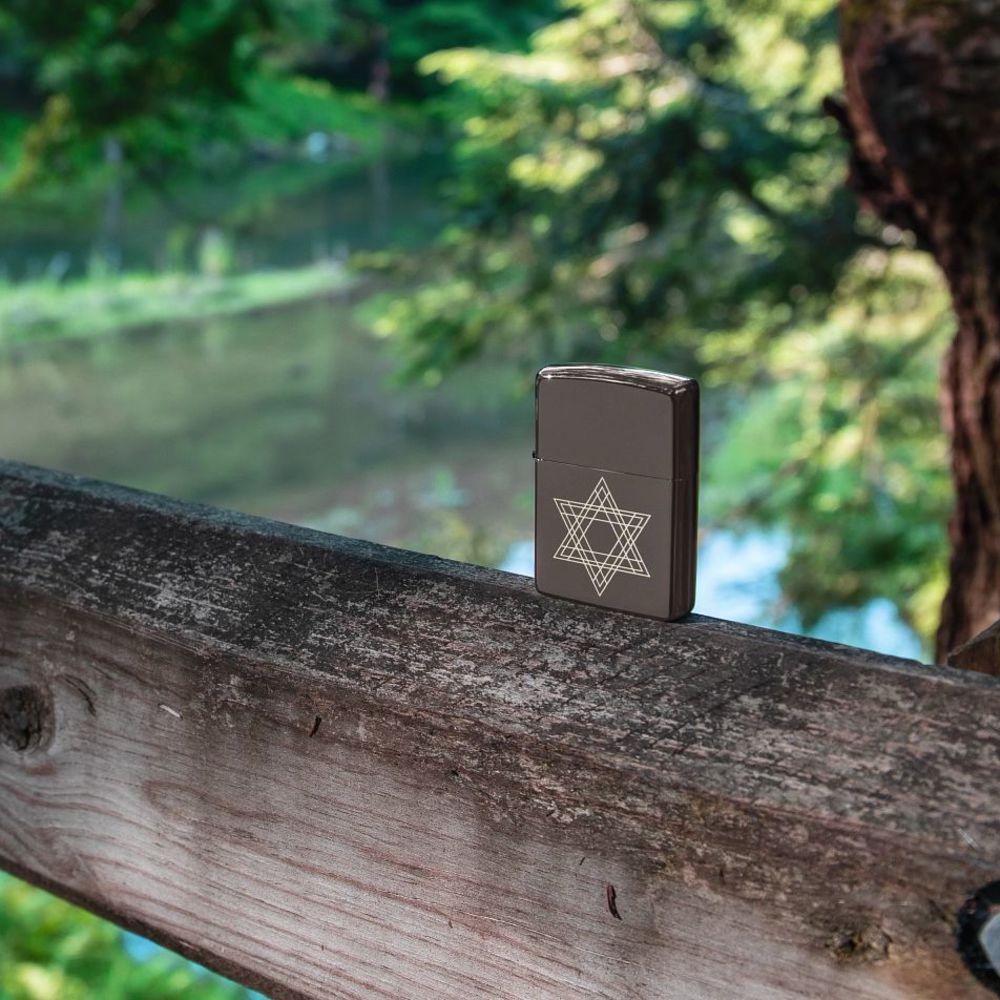 Lifestyle image of Star of David Design Black Ice?« Windproof Lighter, standing on a railing outside with water and trees in the background.